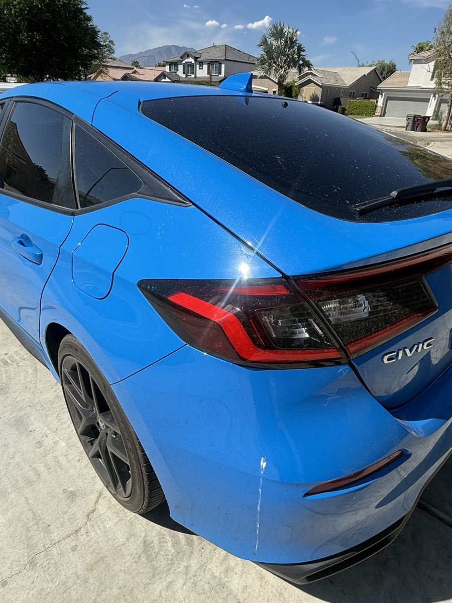 Same Civic rear quarter panel before, covered in water spots and light scratches
