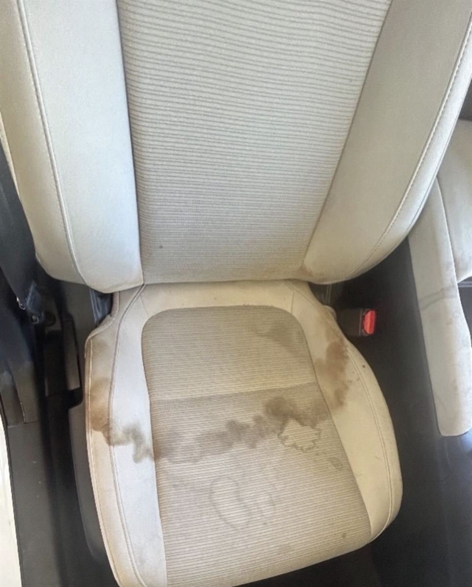 Same tan cloth car seat before, with heavy dark stains