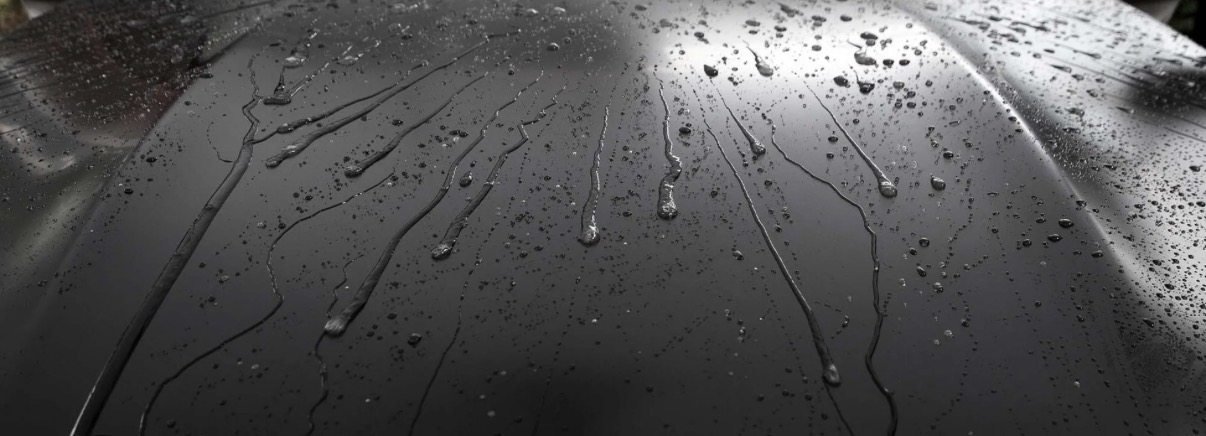 Reference photo of beaded water droplets on a waxed black car panel