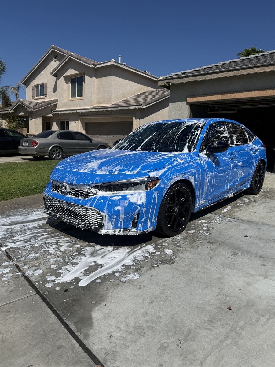 Same blue Honda Civic before detailing, covered in thick foam pre-soak