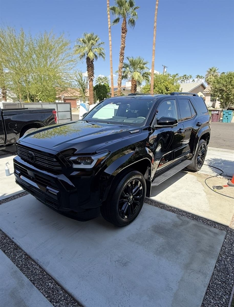 Black Toyota SUV with a glossy, freshly detailed exterior parked in a desert driveway with palm trees